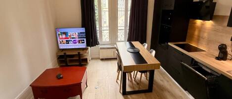 Una sala de estar moderna con televisor, una mesa de comedor y una zona de cocina.