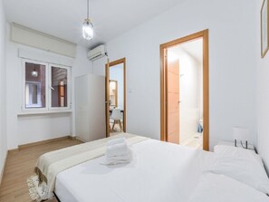 A bedroom with a bed, a window, an air conditioning unit, and a door leading to a bathroom. - Apartment Near Plaza de Espana, Madrid (Madrid)