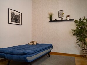 A small room with a single bed, a framed picture on the wall, a shelf with plants, and a large potted plant. - Apartment Near Plaza de Espana, Madrid (Madrid)