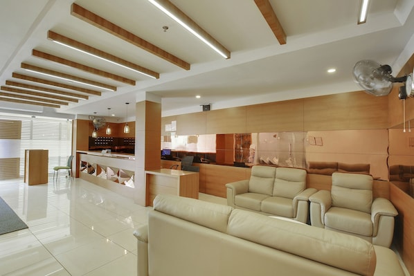 A modern interior with a reception desk, seating area, and kitchen. - Super Townhouse Edasserys Kalamassery (Kanayannur)