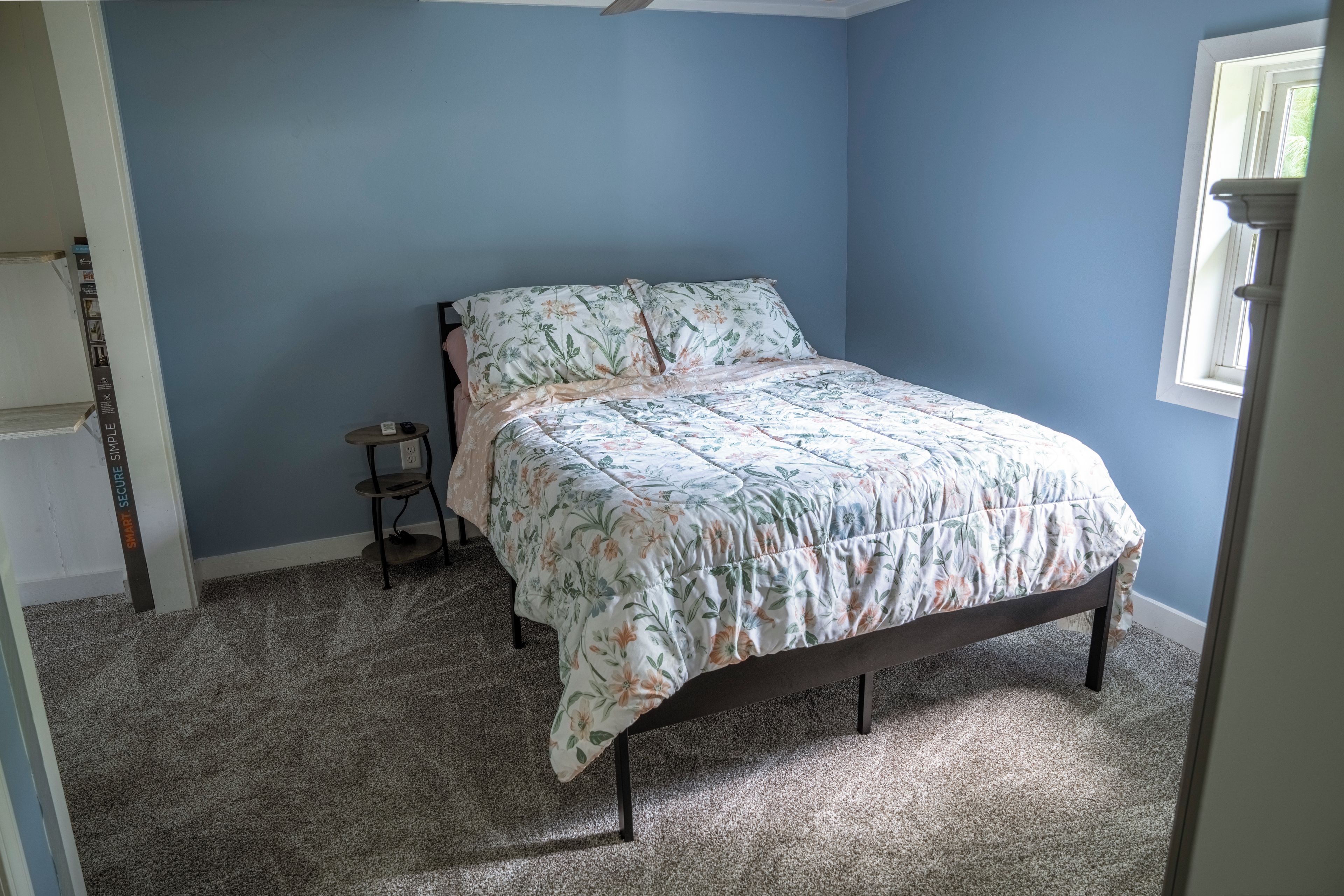 A bedroom with a bed, a small table, and a window.