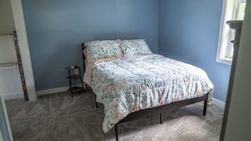 A bedroom with a bed, a small table, and a window.