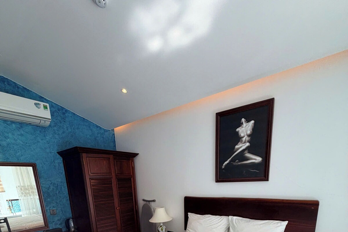 Een hotelkamer met een groot bed, een bureau, een kledingkast en een schilderij aan de muur.
