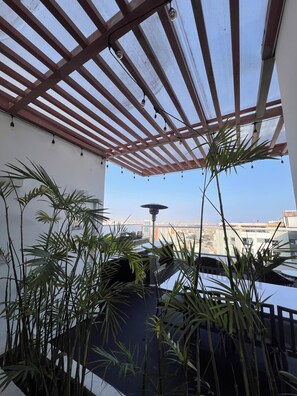 A covered outdoor area with a view of a cityscape, featuring a pergola structure and potted plants. - Vrbo Property (Barranco)