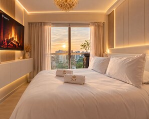 A hotel room with a large bed, a flat-screen TV, a city view, and a chandelier. - Vrbo Property (Barranco)