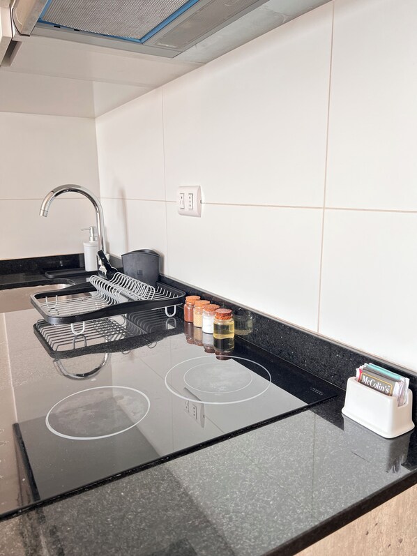 A modern kitchen with a black countertop, stainless steel appliances, and a built-in range hood. - Vrbo Property (Barranco)