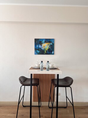 A dining area with a table set for two, two chairs, and a painting on the wall. - Vrbo Property (Barranco)