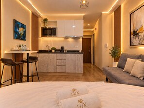 A modern hotel room with a bed, a sofa, a small kitchen area, and a dining table. - Vrbo Property (Barranco)