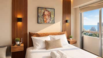 Ein modernes Hotelzimmer mit einem großen Bett, einem Gemälde an der Wand und Blick auf die Stadt durch das Fenster.
