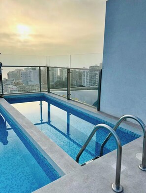 A rooftop pool with a glass balustrade, surrounded by a cityscape view. - Vrbo Property (Barranco)