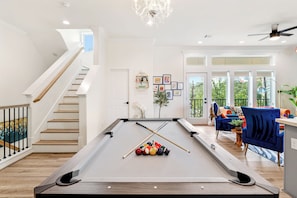 A pool table with billiard balls, a staircase, and a living area with a blue chair and a plant. - Rooftop Cinema Under the Stars +  Prime Location (Houston)
