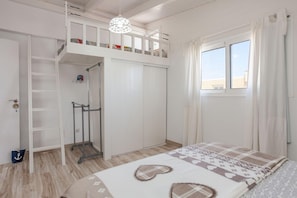 A bedroom with a bunk bed, a wardrobe, a hanging light fixture, and a window with curtains. - Apartment Near Las Cavellinas Beach (La Oliva)