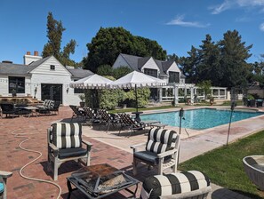 Un espace aménagé au bord de la piscine, avec des chaises longues, des parasols et un foyer.