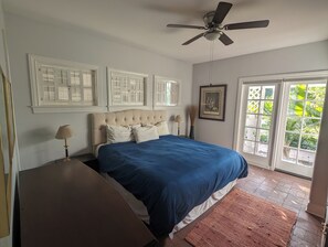 A bedroom with a bed, a ceiling fan, a window with shutters, and a door leading outside. - Quiet 1-bdrm guest house on 2.5 Acre private gated estate in Central Phoenix (Phoenix)