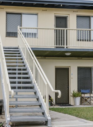 A two-story residential building with a metal staircase, a gated entrance, and a small outdoor seating area. - Beach Retreat & City Views (Henley Beach South)