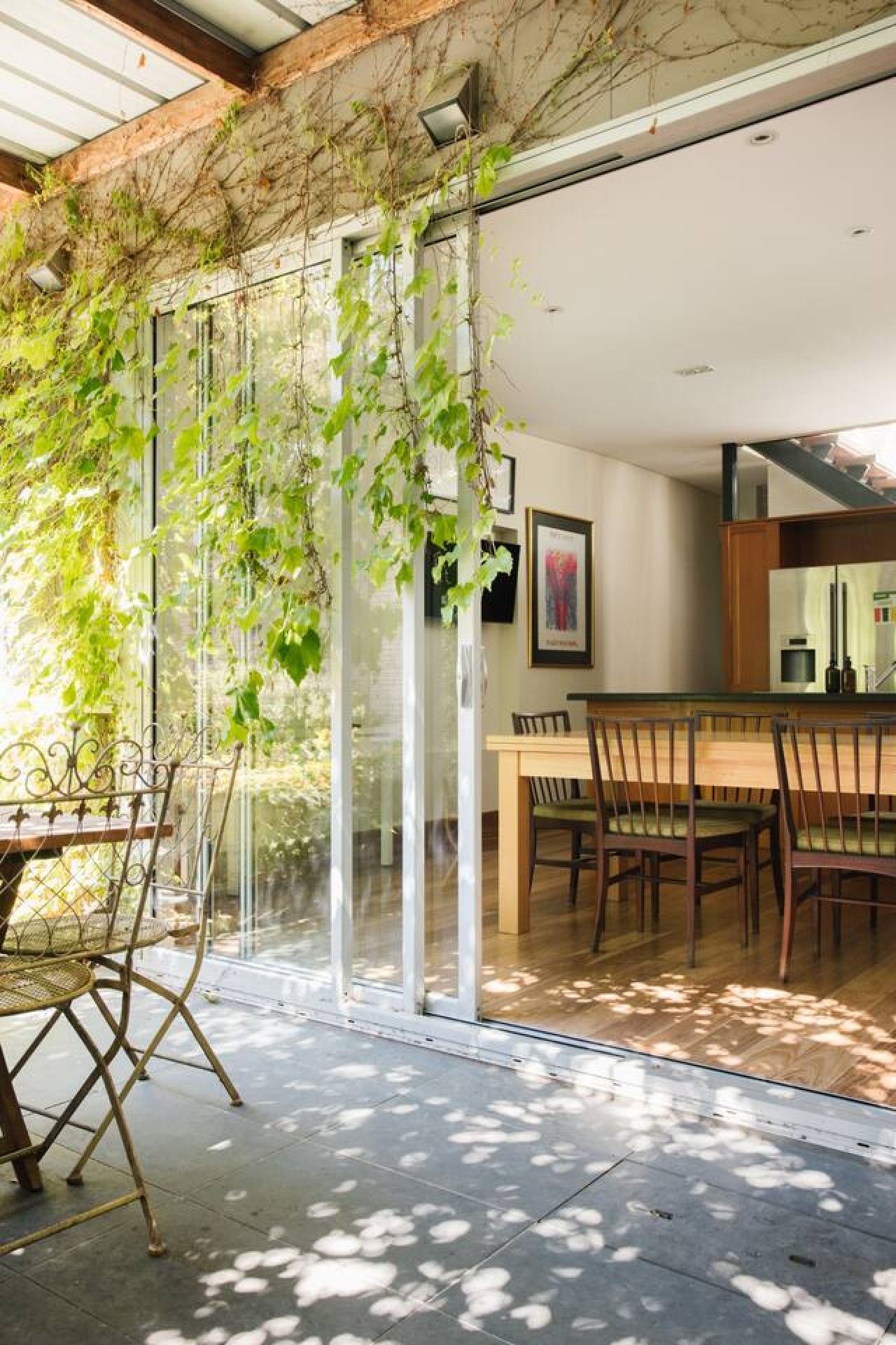 Un comedor con puerta de vidrio que da a un patio, una mesa de madera y sillas.