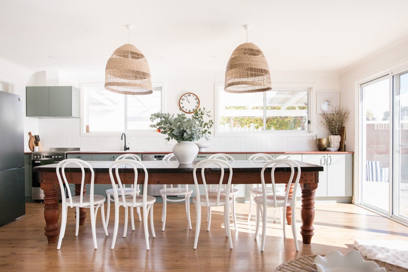 A kitchen with a central island, white chairs, and two hanging pendant lights.