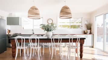 A kitchen with a central island, white chairs, and two hanging pendant lights.