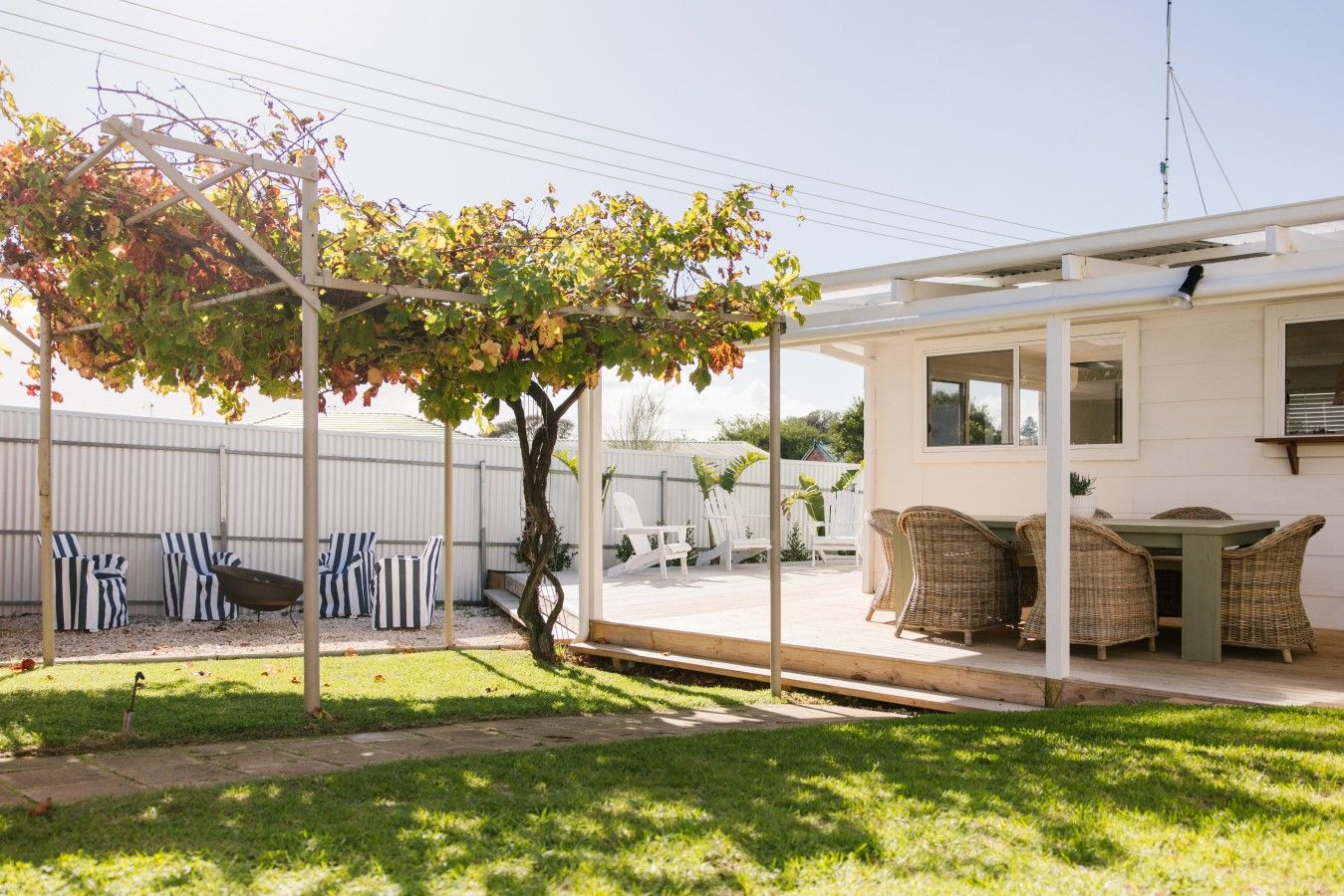 A covered outdoor seating area with wicker furniture and a pergola with vines.