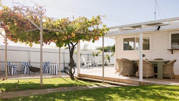 A covered outdoor seating area with wicker furniture and a pergola with vines.