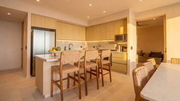 A modern kitchen with a central island, wooden chairs, and a dining table.