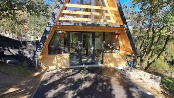 A triangular wooden structure with a glass entrance, surrounded by trees.