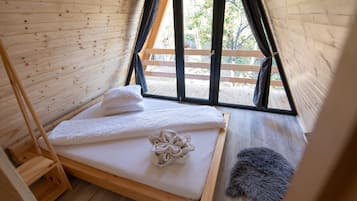 A wooden interior with a bed, a window, and a view of the outside.