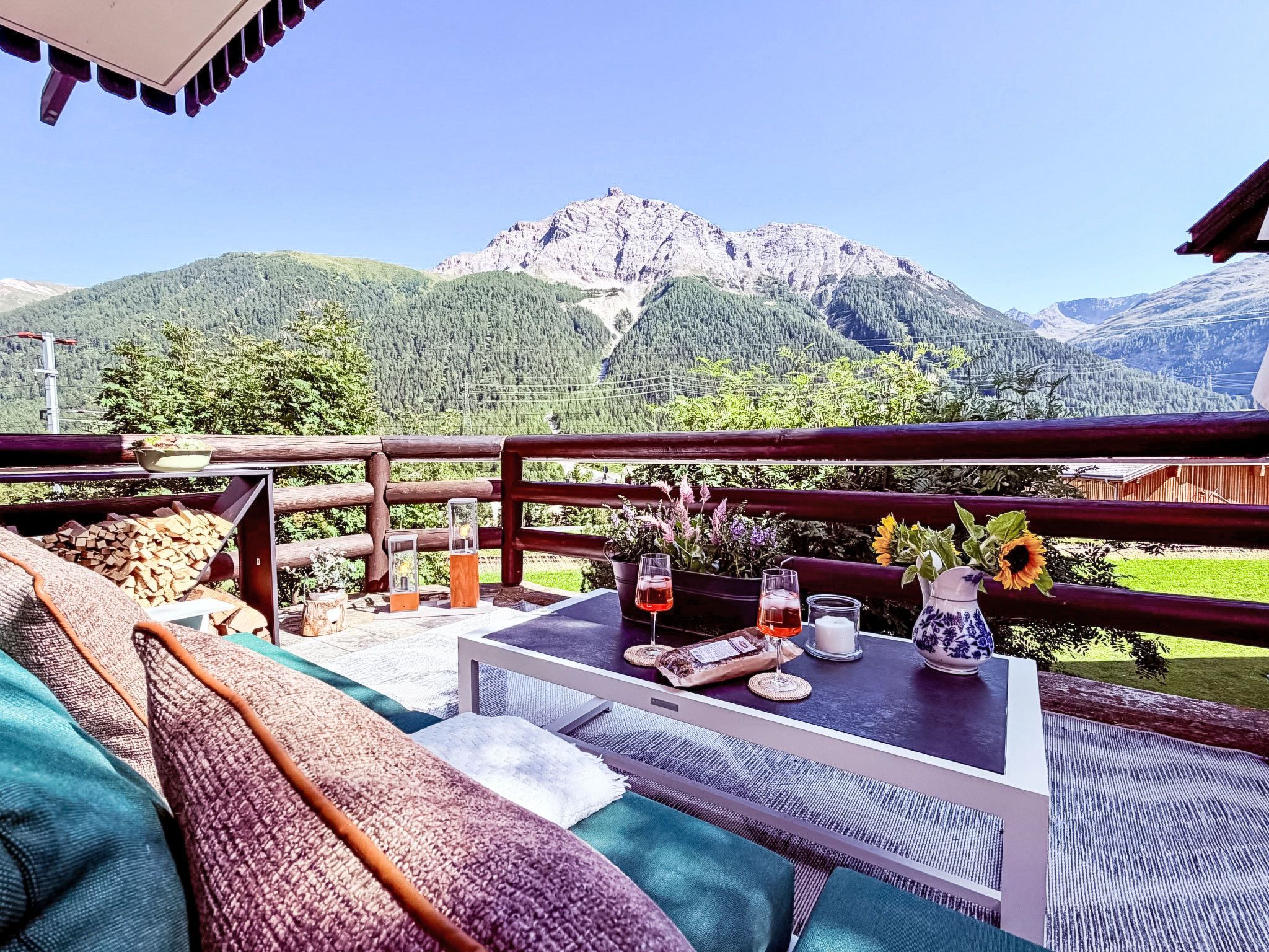 Eine Terrasse mit Tisch für zwei Personen mit Blick auf eine gebirgige Landschaft.