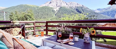 Een terras met een gedekte tafel voor twee, met uitzicht op een bergachtig landschap.