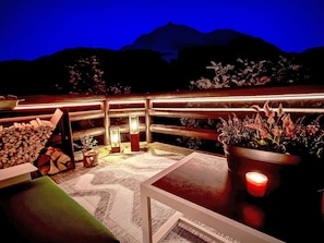 An outdoor seating area with a view of mountains at dusk, featuring a table, chairs, and potted plants. - Cozy Retreat near St. Moritz by Interhome (Madulain)