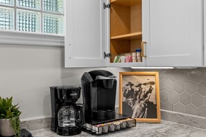 Eine Küche mit Kaffeemaschine, einem Schrank mit Foto und einem Topfpflanzen.