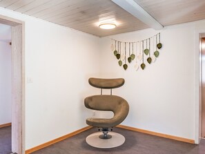 Une pièce d’angle dotée d’un fauteuil au design incurvé original, d’une décoration murale en forme de feuille et d’un plancher en bois.