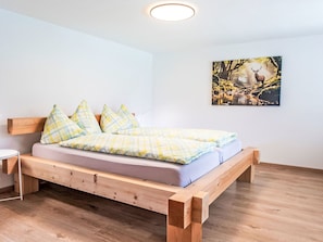 A single bed with a wooden frame, a headboard, and a mattress with a checkered blanket. - Ferienwohnung Enzian by Interhome (Lungern)