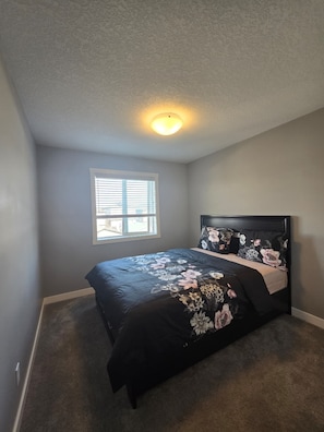 A bedroom with a bed, a window, and a ceiling light. - Executive Home with Garage and Backyard - Near airport and park (Calgary)