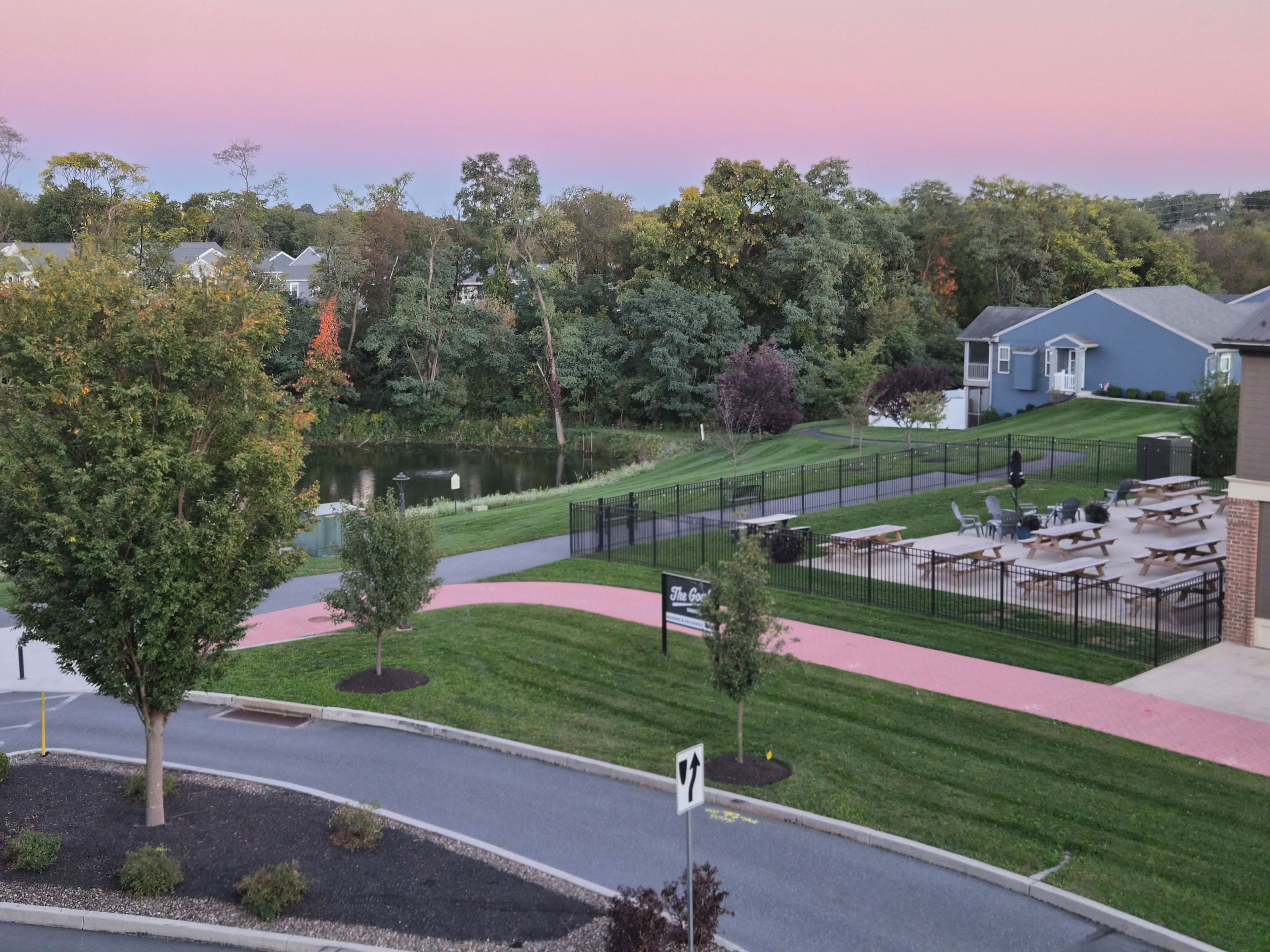 A park with picnic tables, a walking path, and a body of water.