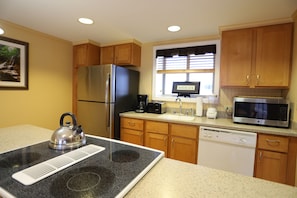 A kitchen with wooden cabinets, a stainless steel refrigerator, a microwave, a dishwasher, and a kettle on the stove. - Enjoy a week of Skiing in Lincoln! (Lincoln)