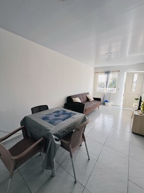 A dining area with a table and chairs, a sofa, and a view of the outside. - Sariebay 3 Condo (San Andrés)