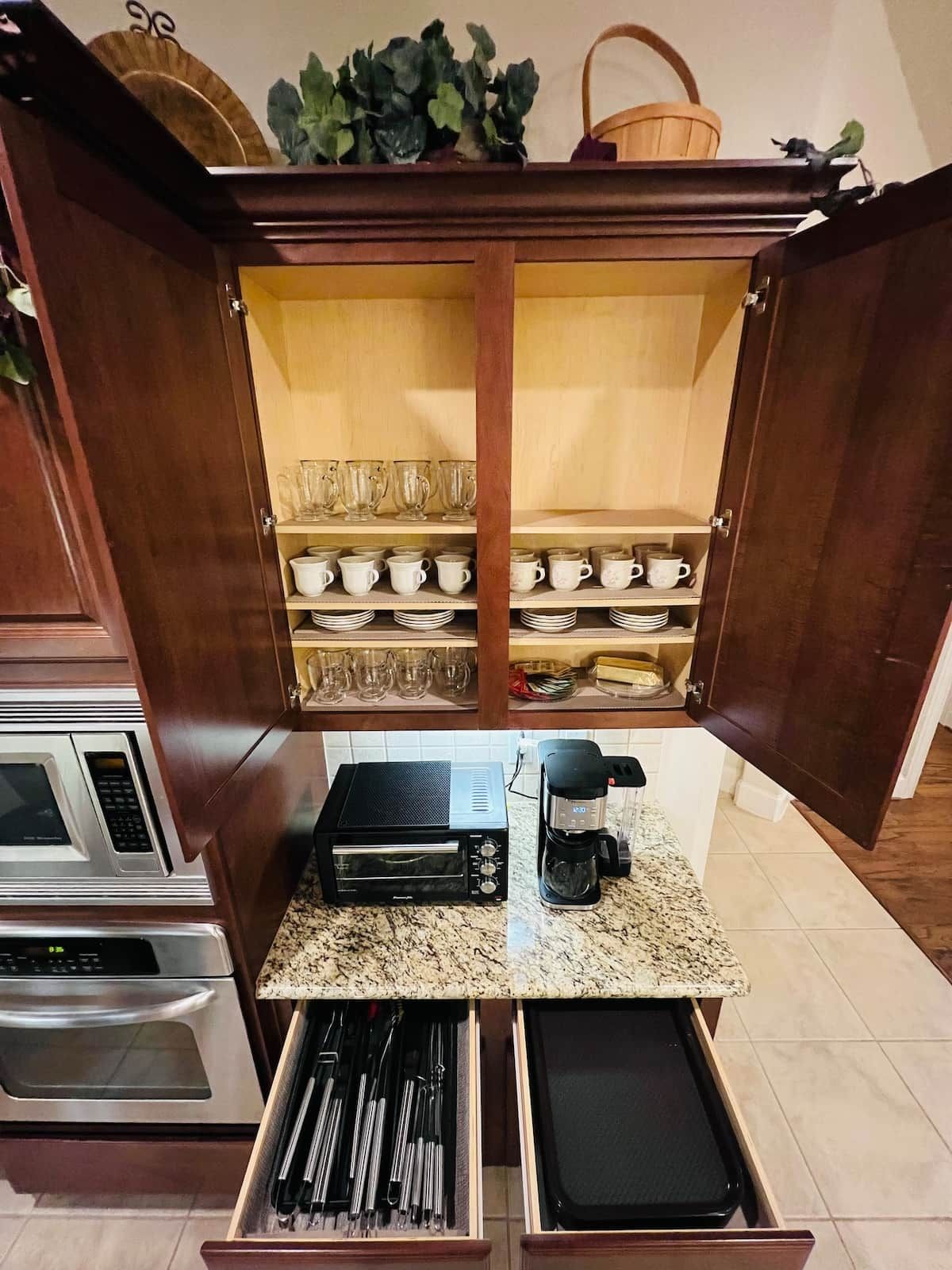 Una cocina equipada con microondas, tostadora, cafetera y un cajón con utensilios.