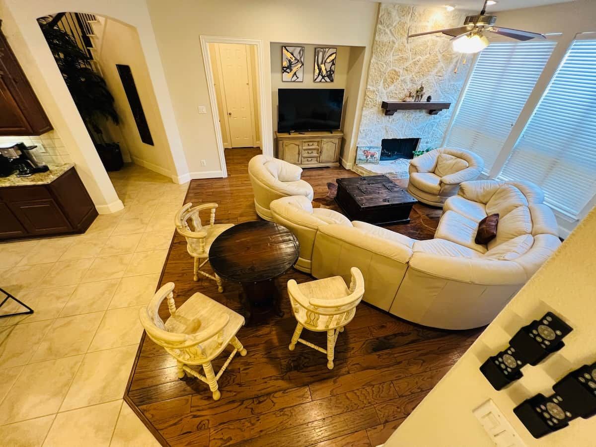 Een woonkamer met een hoekbank, twee fauteuils, een salontafel en een open haard.