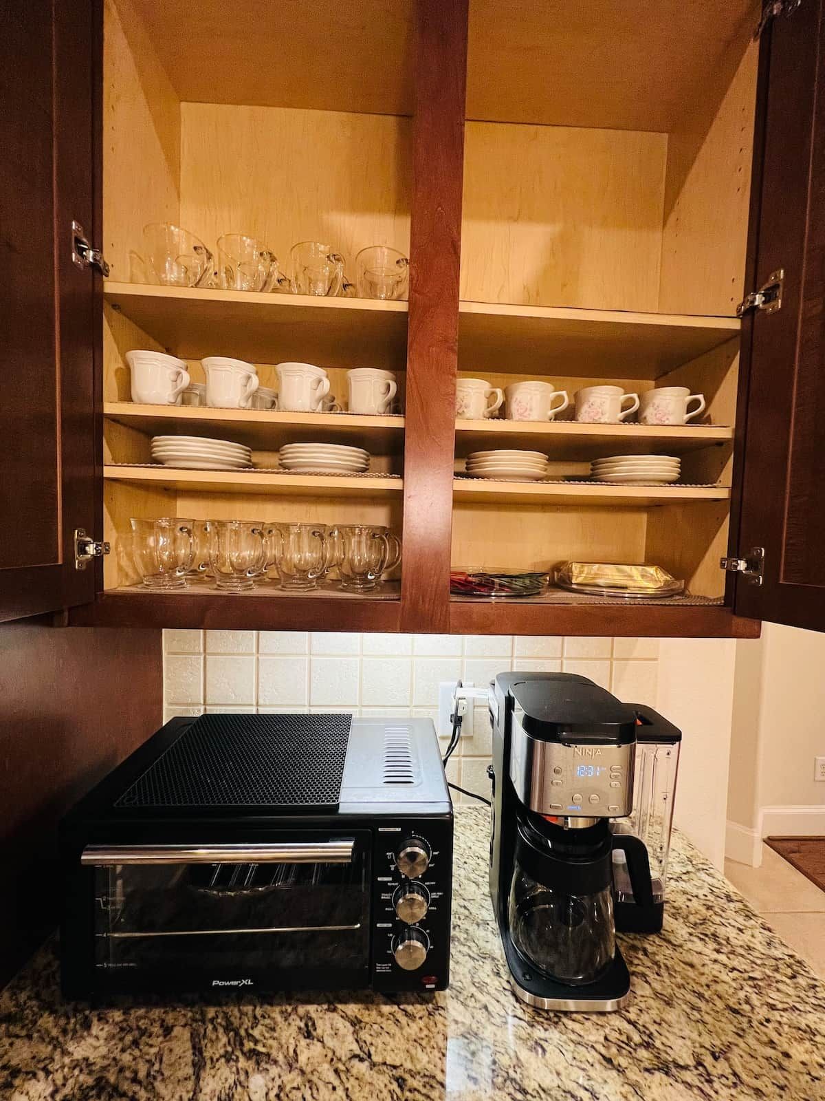 Een keuken met houten kastjes, een toasteroven en een koffiezetapparaat op een granieten aanrecht.