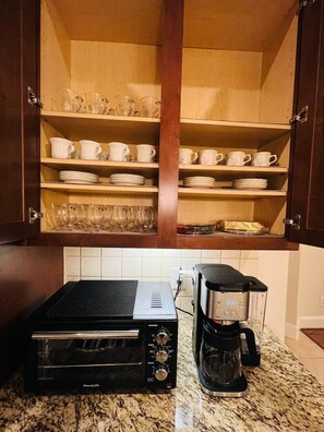 Een keuken met houten kastjes, een toasteroven en een koffiezetapparaat op een granieten aanrecht.