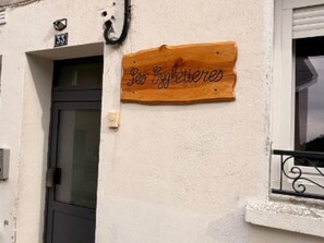 En träskylt med texten ”Por Elegibles” på en byggnads yttervägg.