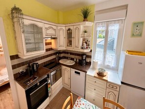A compact kitchen with white cabinets, a sink, a stove, and a refrigerator. - Family Apartment in Mont-dore (Mont-Dore)