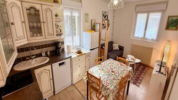 A compact kitchen with a sink, stove, and dining area with chairs.