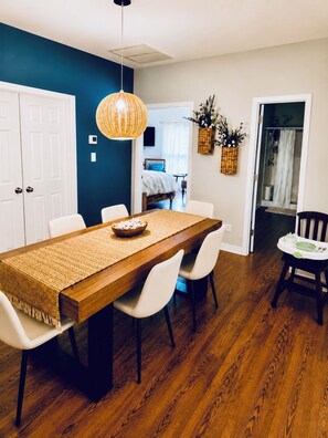 A dining area with a wooden table, white chairs, and a woven placemat. - Resting Beach Face Sleeps 10, 2 Kings, Bunks, Mini Bar, 2 Pools, Beach 6 Blocks (Gulf Shores)
