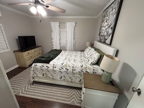 A bedroom with a bed, a dresser, a TV, a ceiling fan, and a painting on the wall. - Quiet Waterfront Cabin, Private Dock, Fire Pit, Pet Friendly (Parsons)