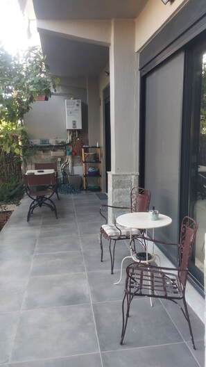An outdoor patio with a table and chairs, a covered area, and a view of the interior. - Alimos Signature Home (Alimos)