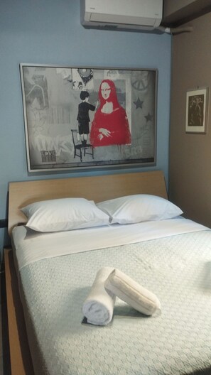 Ein Hotelzimmer mit Bett, Handtuch, einem Gemälde an der Wand und einem gerahmten Bild.