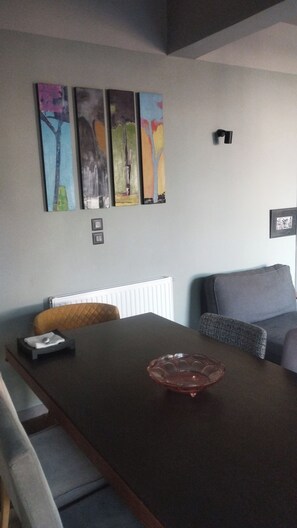 Ein modernes Wohnzimmer mit einem dunklen Holztisch, einem Glastisch, einem grauen Sofa und einer Heizung.