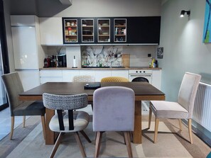 A modern kitchen with a dining table, chairs, and cabinets. - Alimos Signature Home (Alimos)